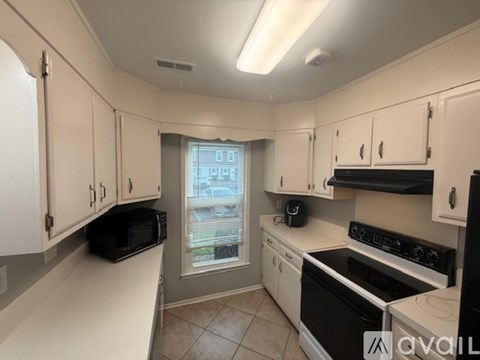 A kitchen with white cabinets and black appliances.