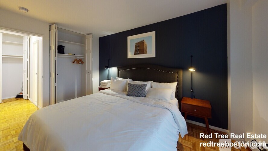 A bedroom with a bed, nightstand, and a picture on the wall.