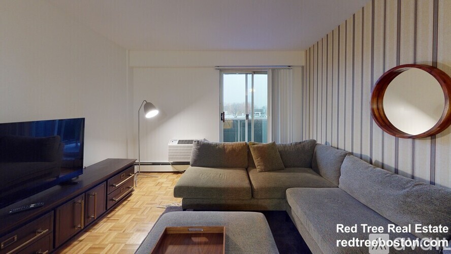 A living room with a couch, a television, and a mirror on the wall.