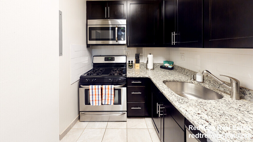 A kitchen with black cabinets and a stove top oven.