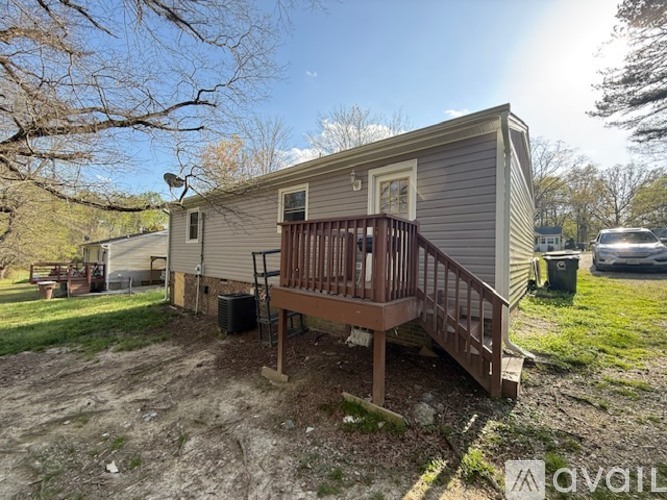 A mobile home with a deck and a trash can in front.