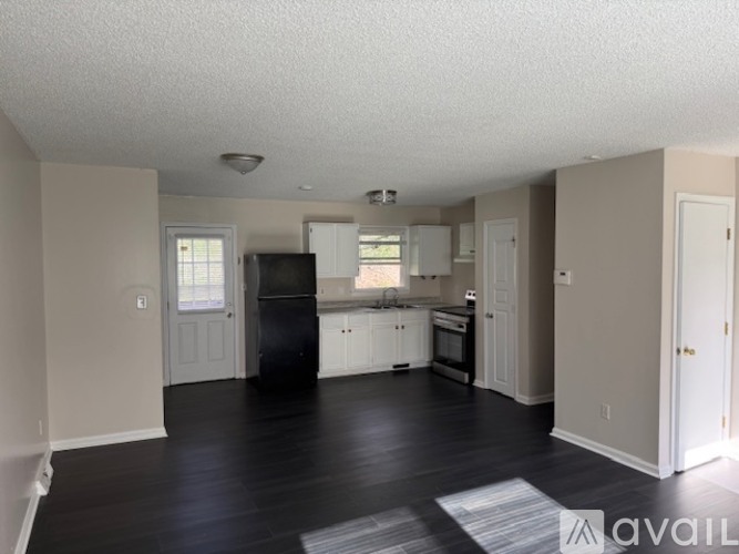 A kitchen with white cabinets and a black fridge is available.