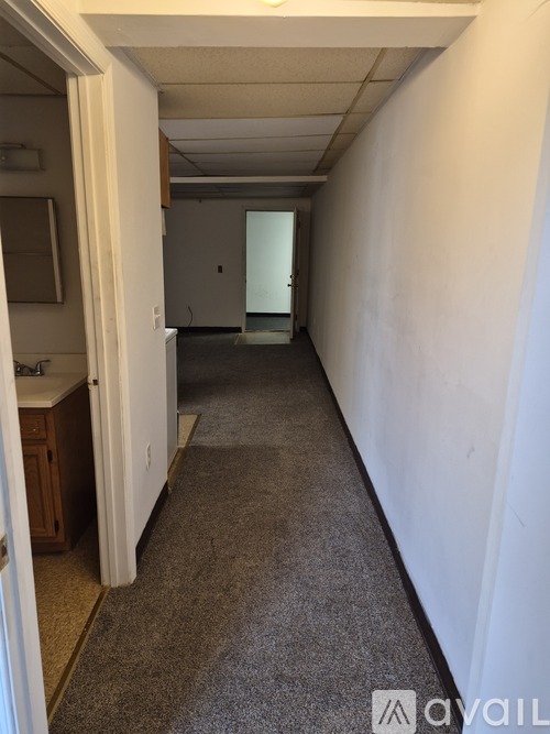 A long hallway with a carpeted floor and white walls.