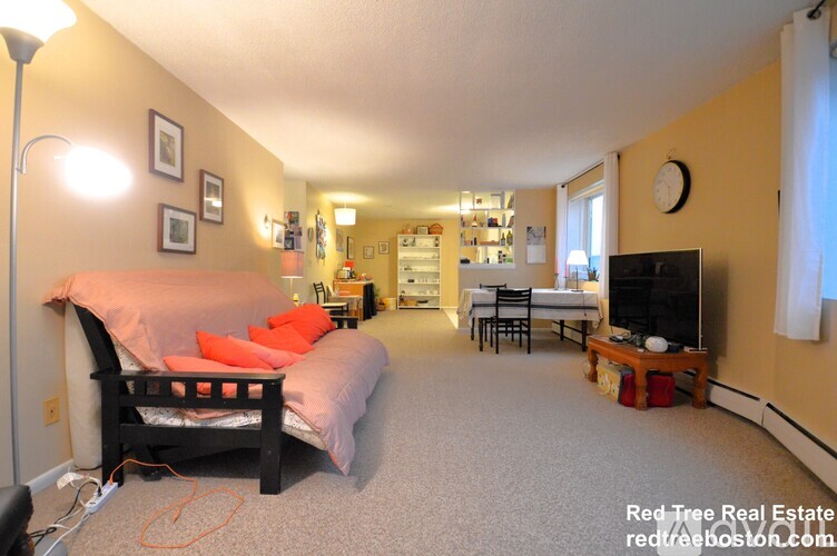 A bedroom with a bed, a couch, and a television.