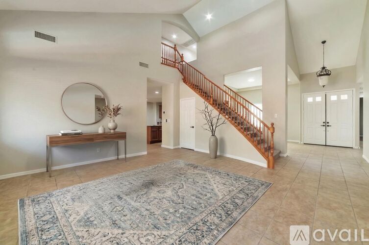 A spacious living room with a staircase and a rug.