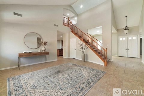 A spacious living room with a staircase and a rug.
