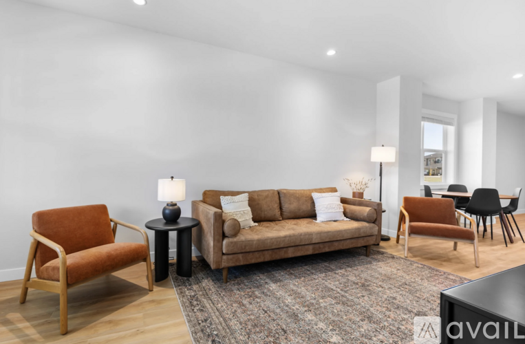 A living room with a brown sofa, a wooden chair, and a black table.