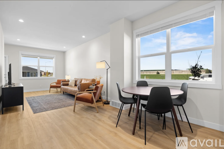 A modern living room with a large window and a dining table set up.