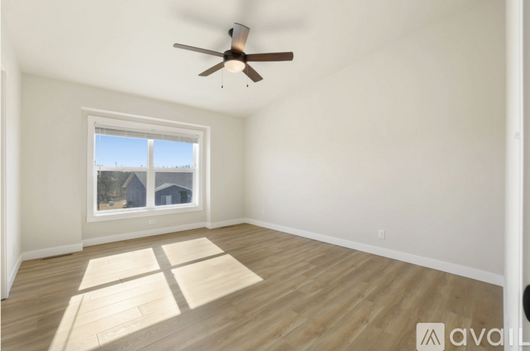 A bedroom with a large bed and a window overlooking a residential area.