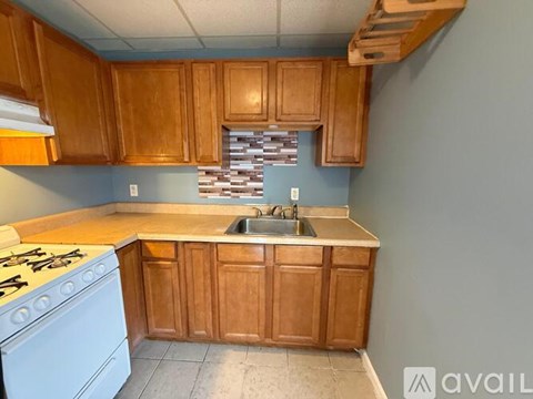 A kitchen with wooden cabinets and a white stove top oven.