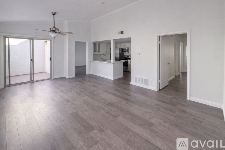 A spacious room with a ceiling fan and wooden flooring.