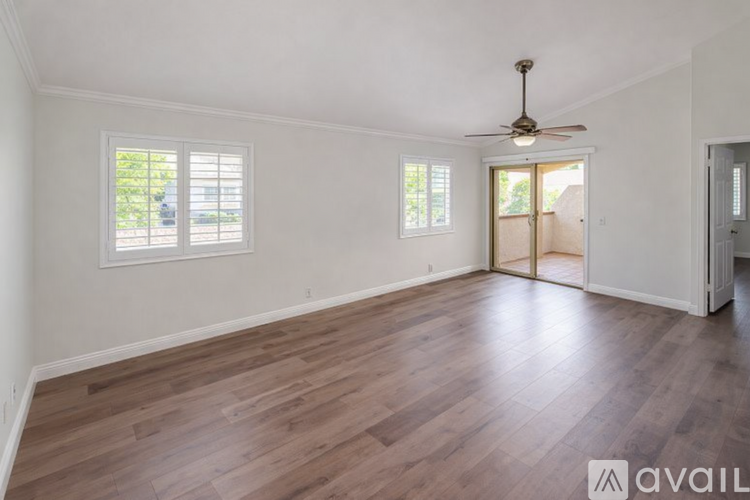 A spacious living room with a sliding glass door leading to a balcony.