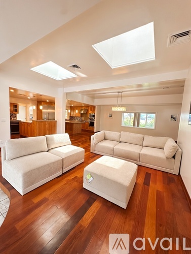 A living room with white furniture and wooden floors.