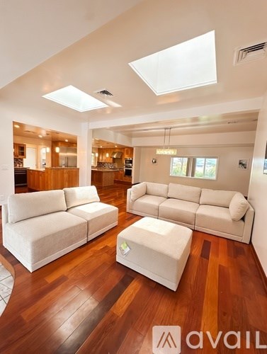 A living room with white furniture and wooden floors.