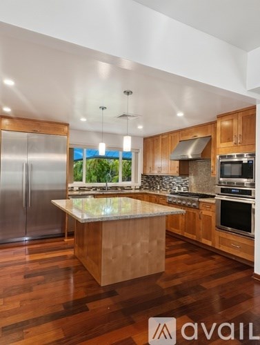 A kitchen with wooden cabinets and a marble island.