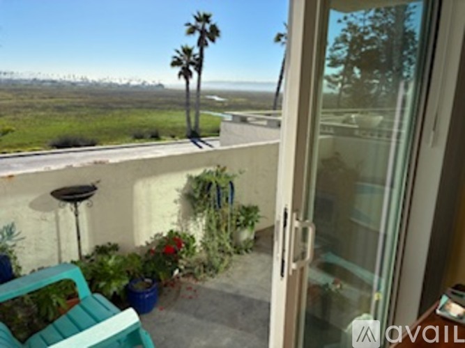 A balcony with a chair and a table with a plant on it.