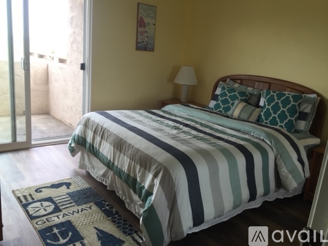 A bedroom with a bed, lamp, and a picture on the wall.