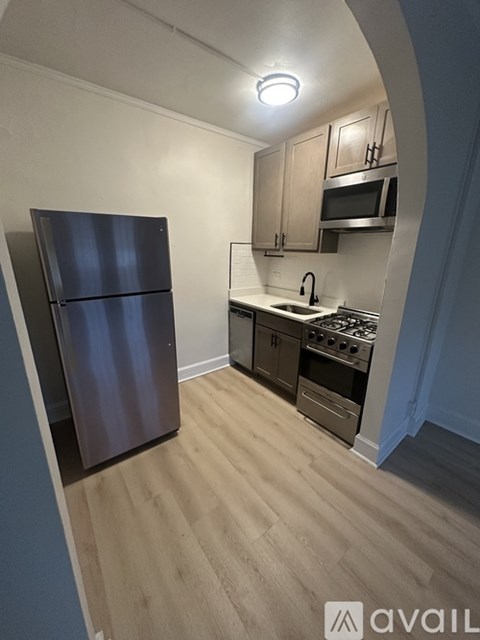 A kitchen with a refrigerator, stove, and cabinets.