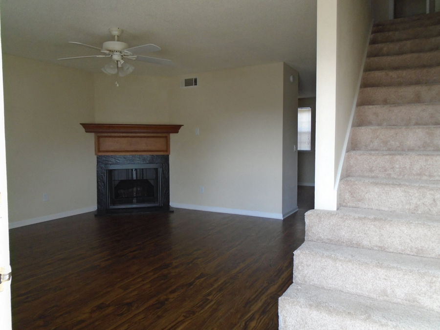 an empty living room with a fireplace and stairs