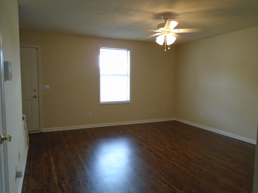 an empty living room with wooden floors and a ceiling fan