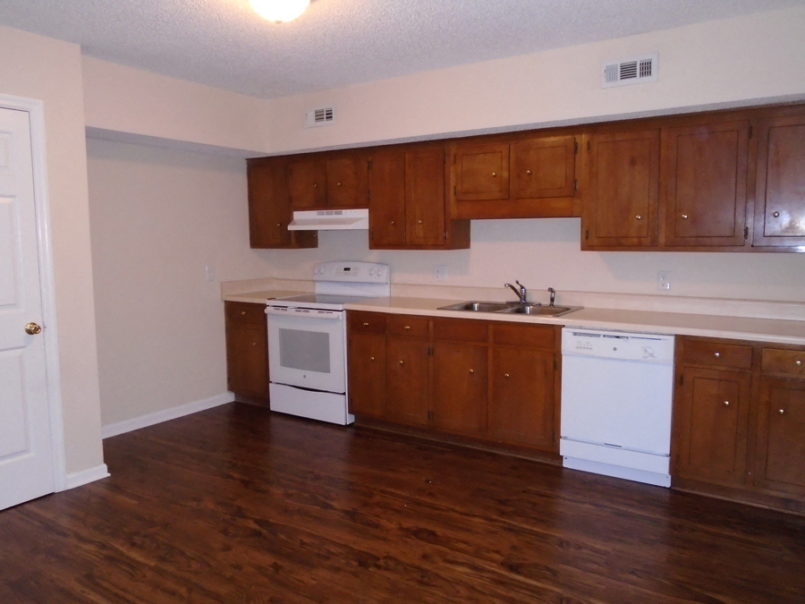 an empty kitchen with wooden cabinets and white appliances
