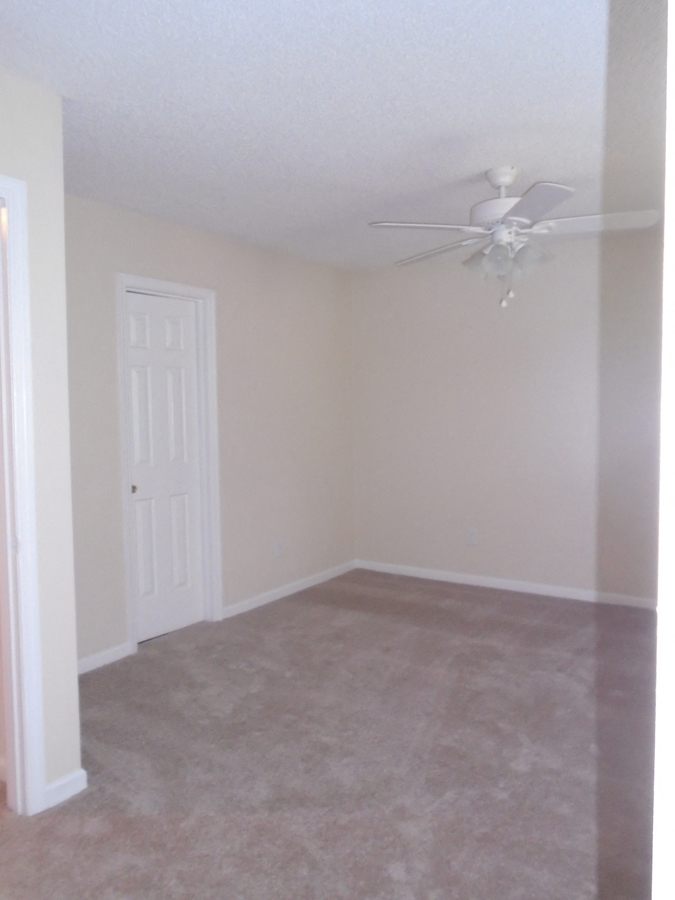 an empty room with a ceiling fan and a white door