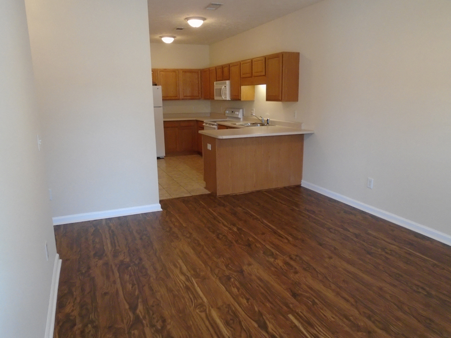 an empty living room and kitchen with wood flooring