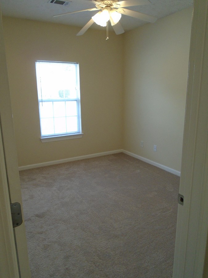 an empty room with a ceiling fan and a window
