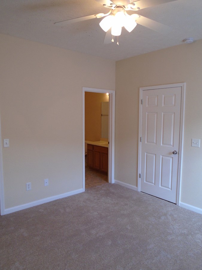 an empty bedroom with a closet and a door to a bathroom