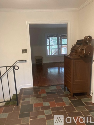 A room with a tiled floor and a wooden cabinet with a vintage typewriter on top.