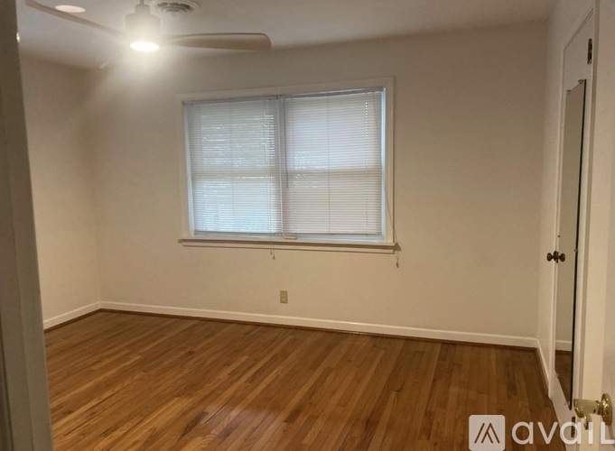 A room with wooden flooring and a window with blinds.