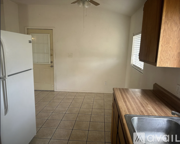 A kitchen with a white fridge, wooden countertop, and a ceiling fan.