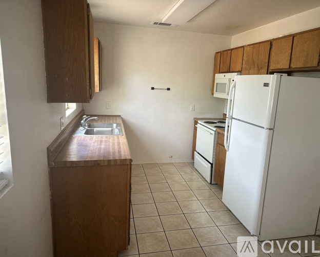 A kitchen with a white refrigerator, wooden cabinets, and a sink.