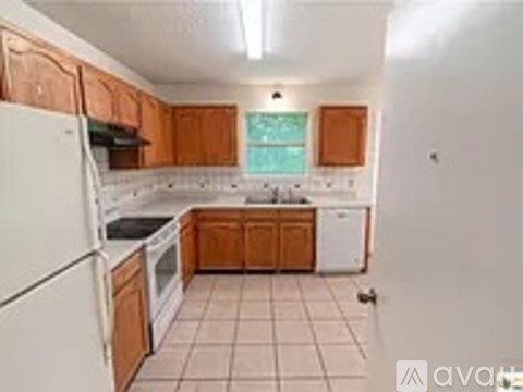 A kitchen with white appliances and wooden cabinets.