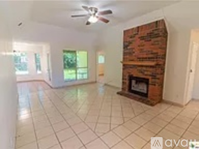 A living room with a brick fireplace and a ceiling fan.