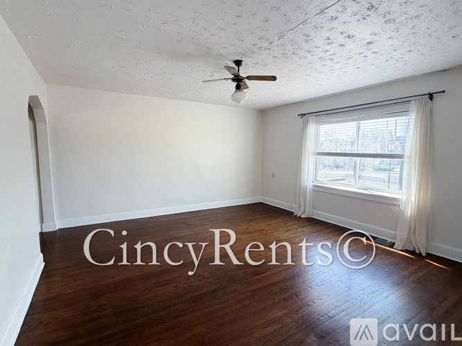 A room with a ceiling fan and a window with curtains.