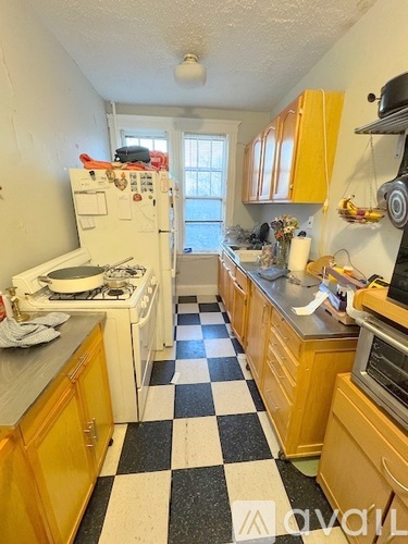 A kitchen with yellow cabinets and a black and white checkered floor.