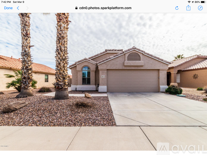 A house with a driveway and two palm trees in front.