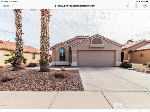 A house with a driveway and two palm trees in front.