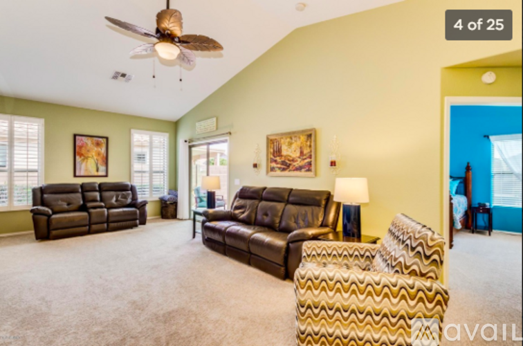 A living room with a brown leather couch and a ceiling fan.