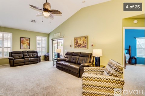 A living room with a brown leather couch and a ceiling fan.