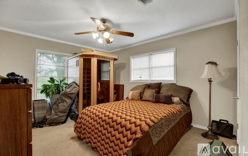 A bedroom with a bed, a ceiling fan, and a window.