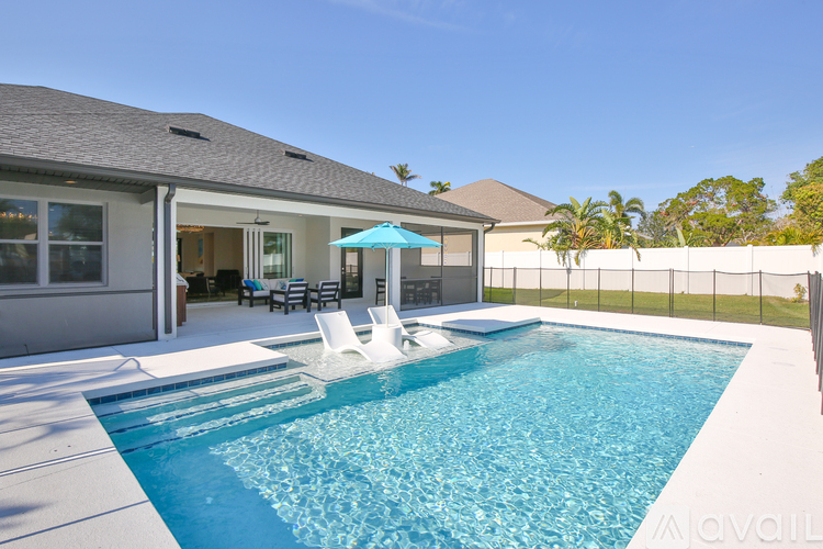 A swimming pool in a backyard with a patio and a house in the background.