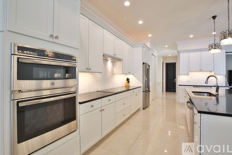 A modern kitchen with white cabinets and stainless steel appliances.