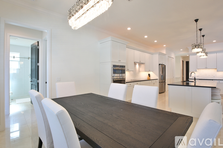 A modern dining room with a wooden table and white chairs.