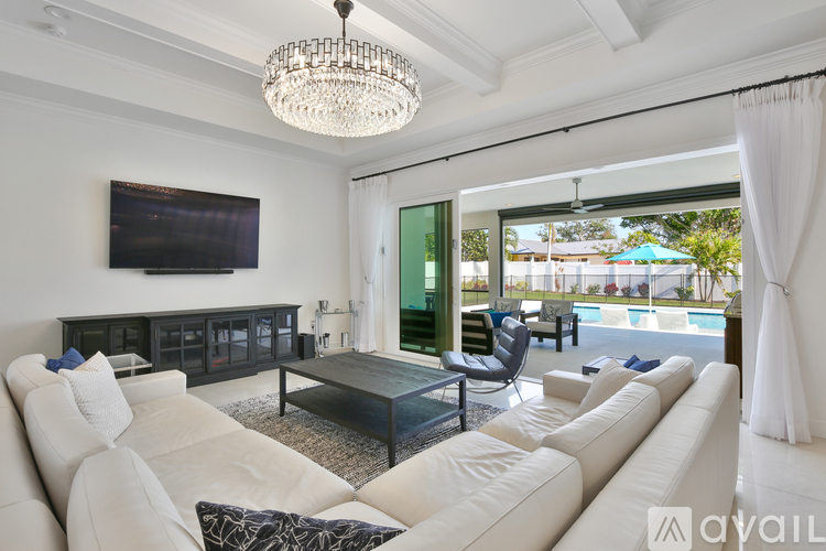 A living room with a white sofa and a television mounted on the wall.