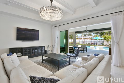 A living room with a white sofa and a television mounted on the wall.