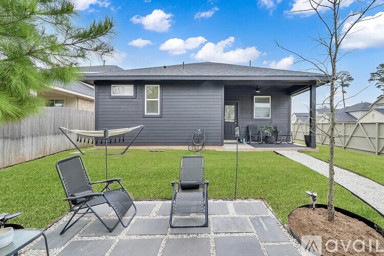 A backyard with a patio, chairs, and a tree.