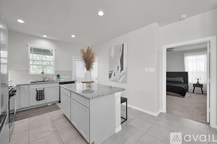A kitchen with white cabinets and a marble island.