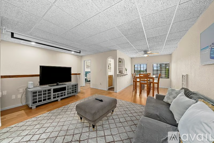 A living room with a television and a grey ottoman.